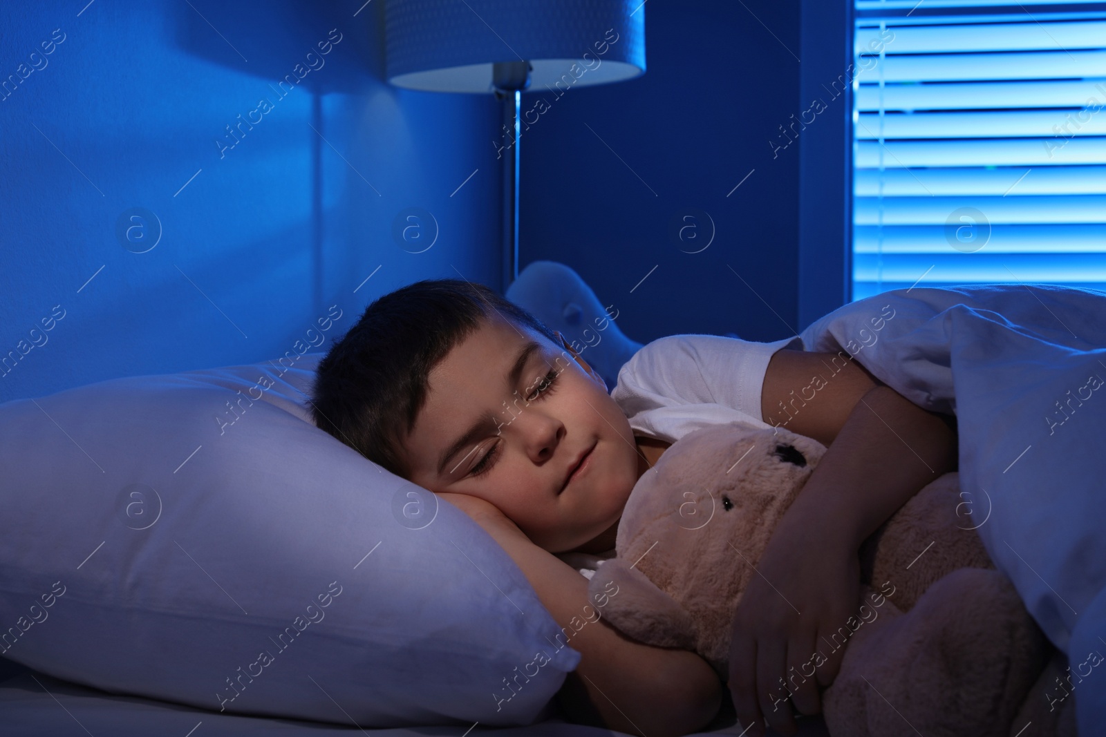 Photo of Little boy sleeping with teddy bear at home. Bedtime