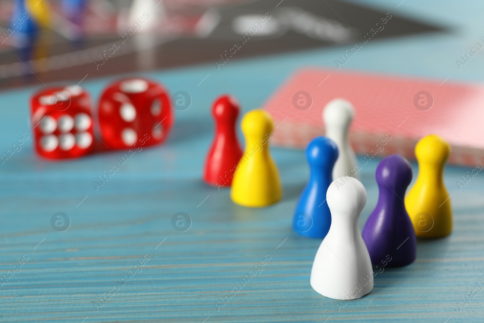 Photo of Closeup view of pawns and dices on light blue wooden table, space for text. Board game