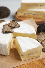 Photo of Soft cheese and fresh truffles on wooden board, closeup