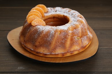 Photo of Homemade yogurt cake with tangerines and powdered sugar on wooden table