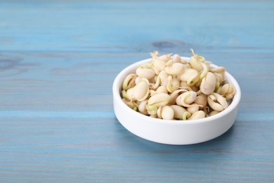 Photo of Sprouted kidney beans in bowl on light blue wooden table, closeup. Space for text