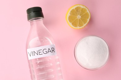 Photo of Eco friendly natural cleaners. Vinegar in bottle, cut lemon and bowl of soda on pink background, flat lay