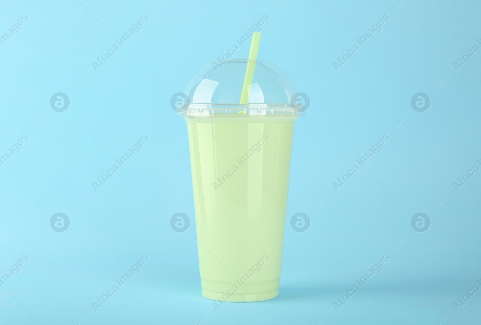 Photo of Plastic cup of tasty smoothie on light blue background