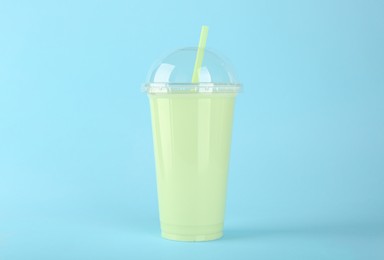 Photo of Plastic cup of tasty smoothie on light blue background