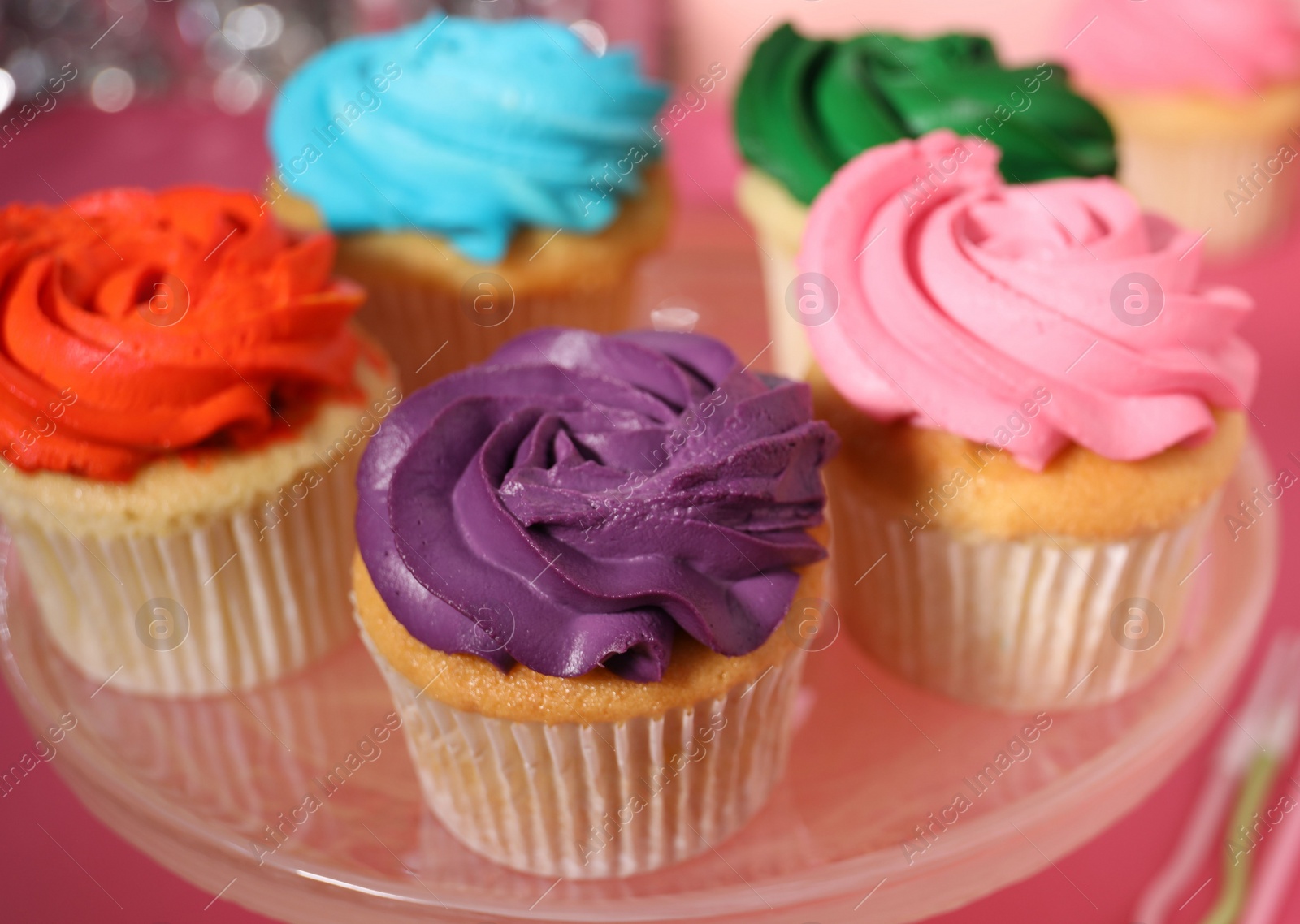 Photo of Delicious cupcakes with bright cream on pink table, closeup