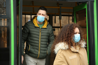 Photo of People with disposable masks going out of bus outdoors. Virus protection