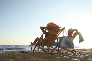 Photo of Young couple relaxing in deck chairs on beach near sea