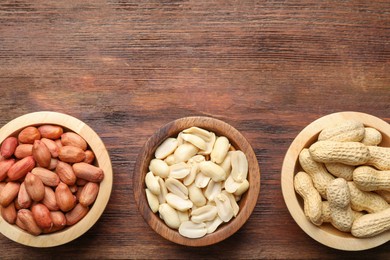Photo of Fresh peanuts in bowls on wooden table, top view