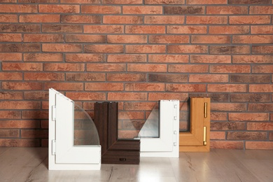 Photo of Samples of modern window profiles on floor against brick wall. Installation service