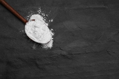 Photo of Wooden spoon of natural starch on black table, top view. Space for text