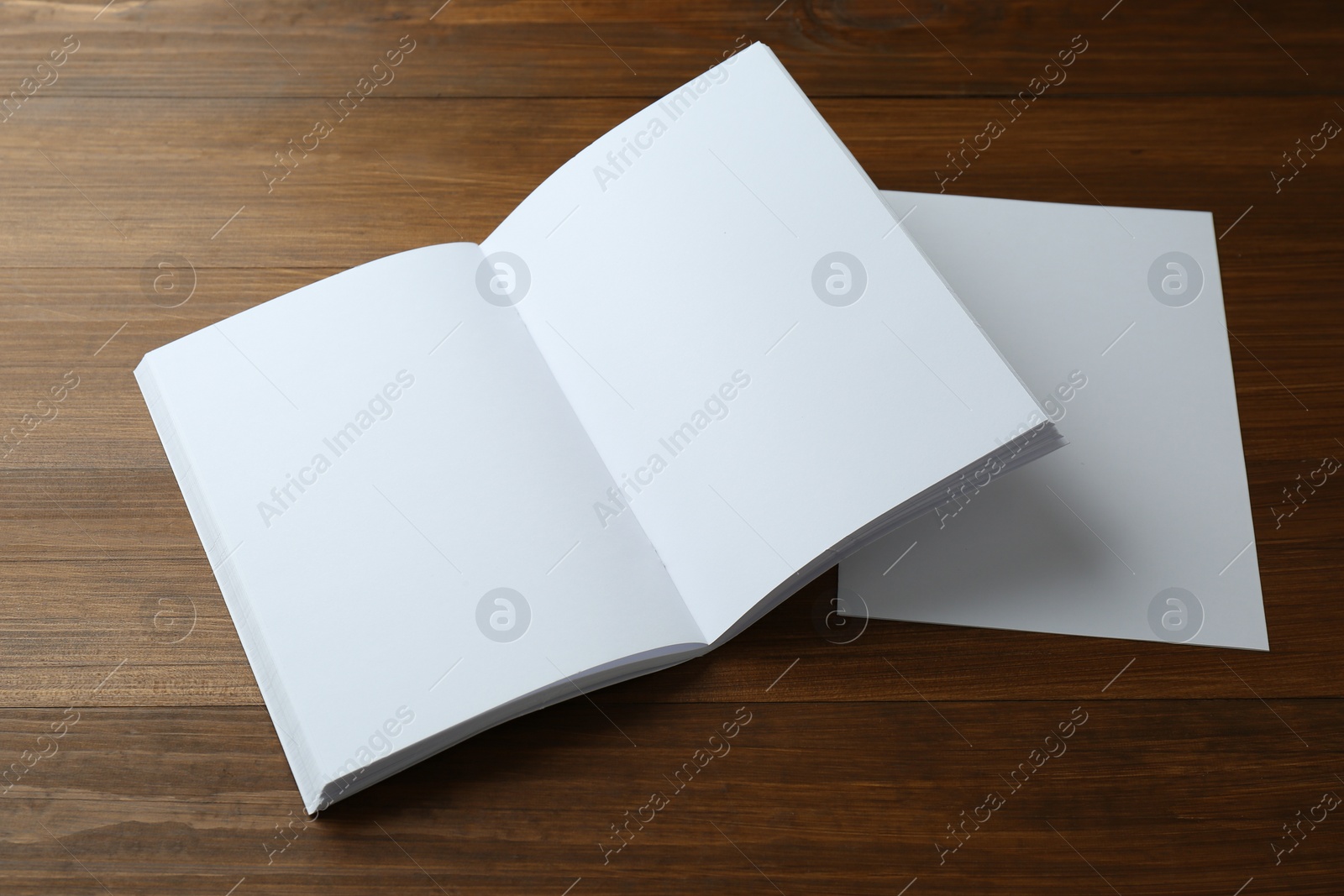 Photo of Sheet of paper and blank brochure on wooden table. Mockup for design