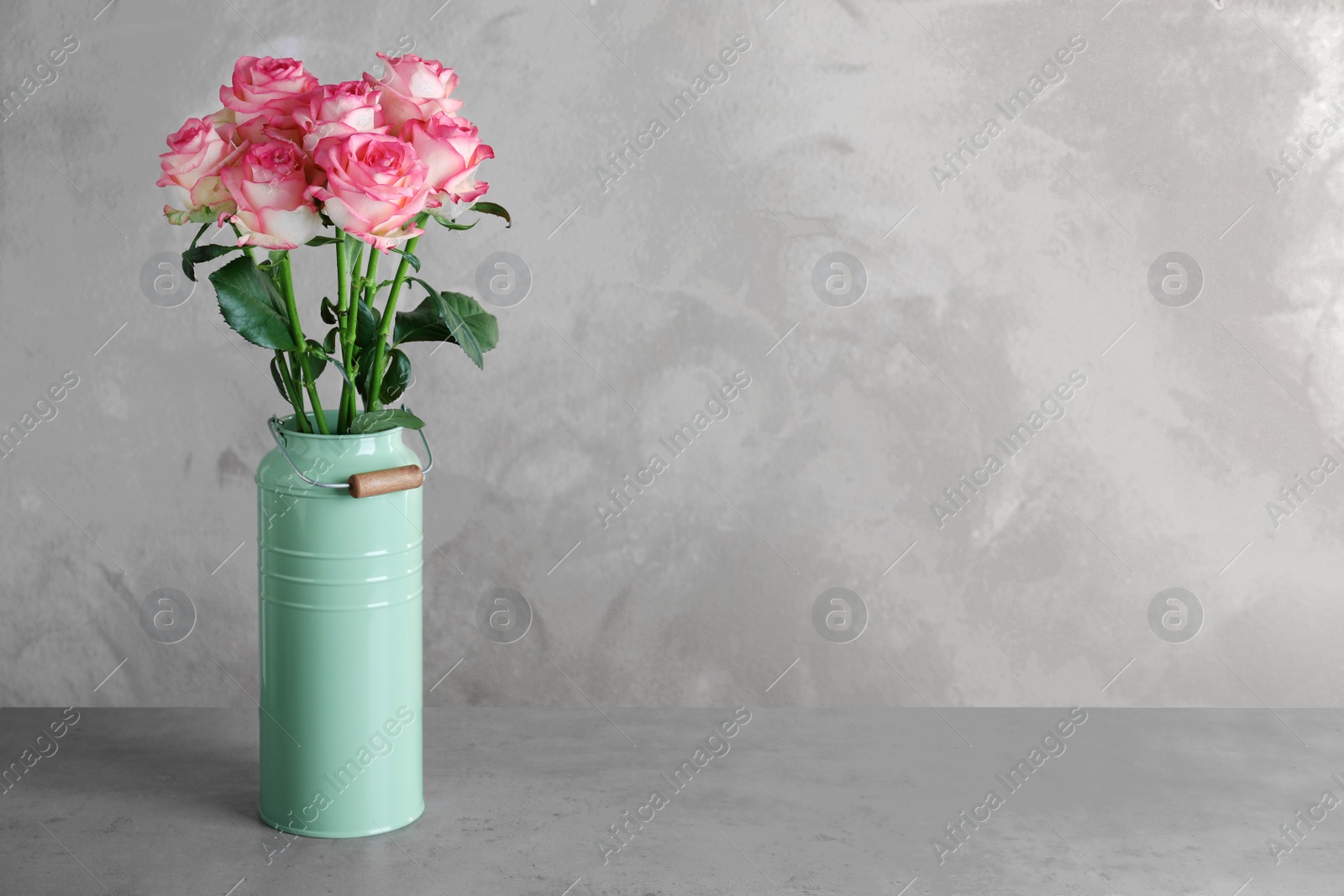 Photo of Vase with beautiful pink roses on grey table. Space for text