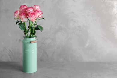 Vase with beautiful pink roses on grey table. Space for text