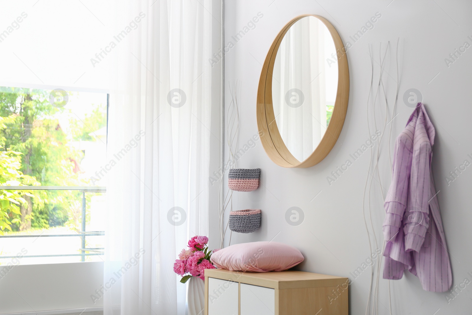 Photo of Stylish hallway interior with round mirror on white wall