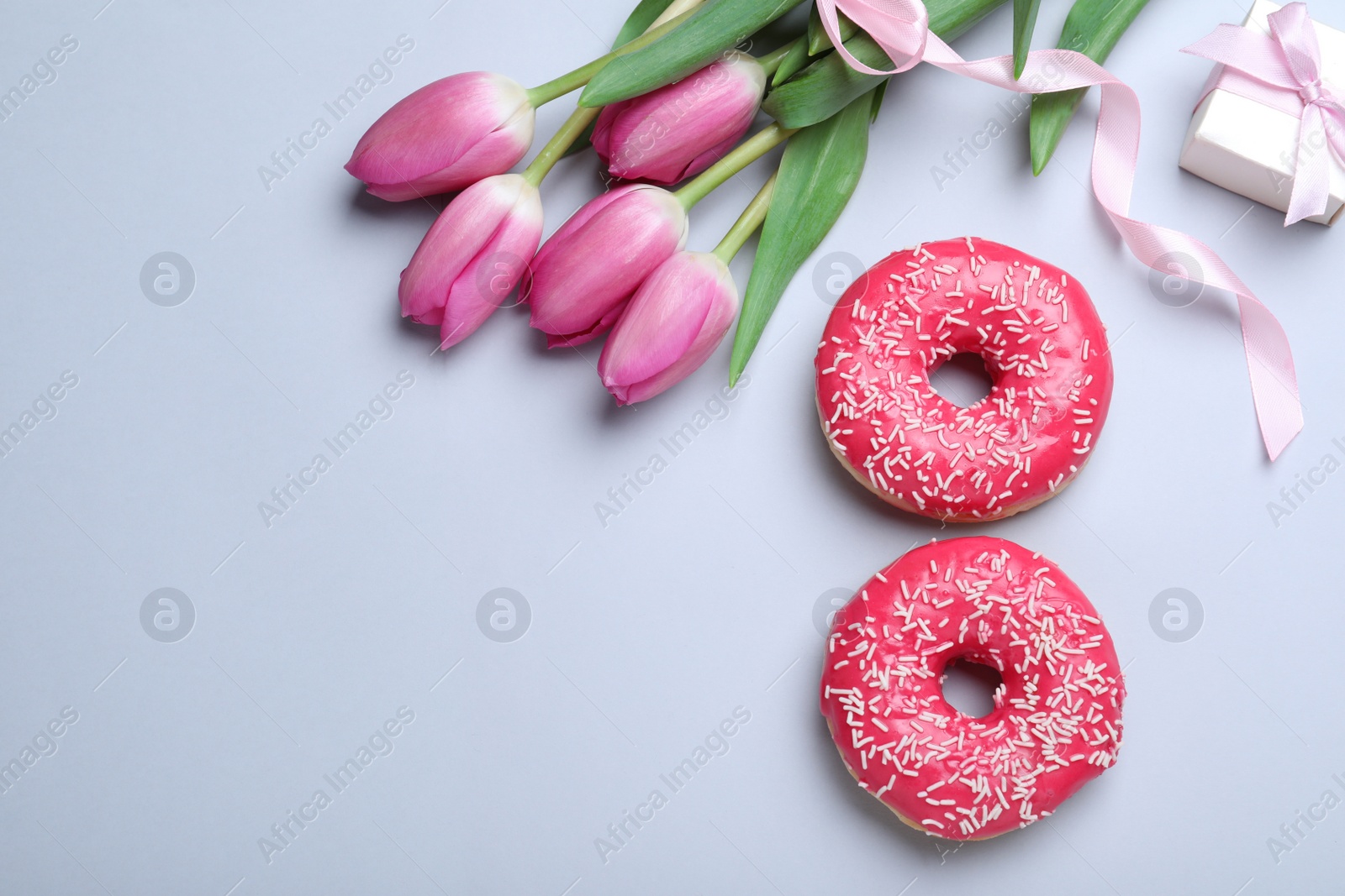 Photo of 8 March greeting card design with tulips, donuts, gift box and space for text on light grey background, flat lay. International Women's day