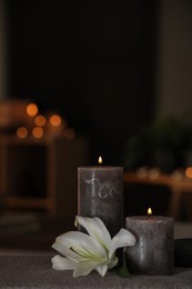 Photo of Spa composition with burning candles, lily flower and stone on massage table in wellness center, space for text