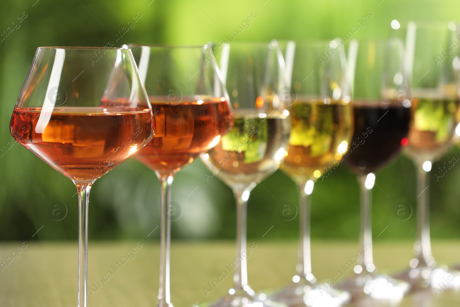 Photo of Different tasty wines in glasses against blurred background