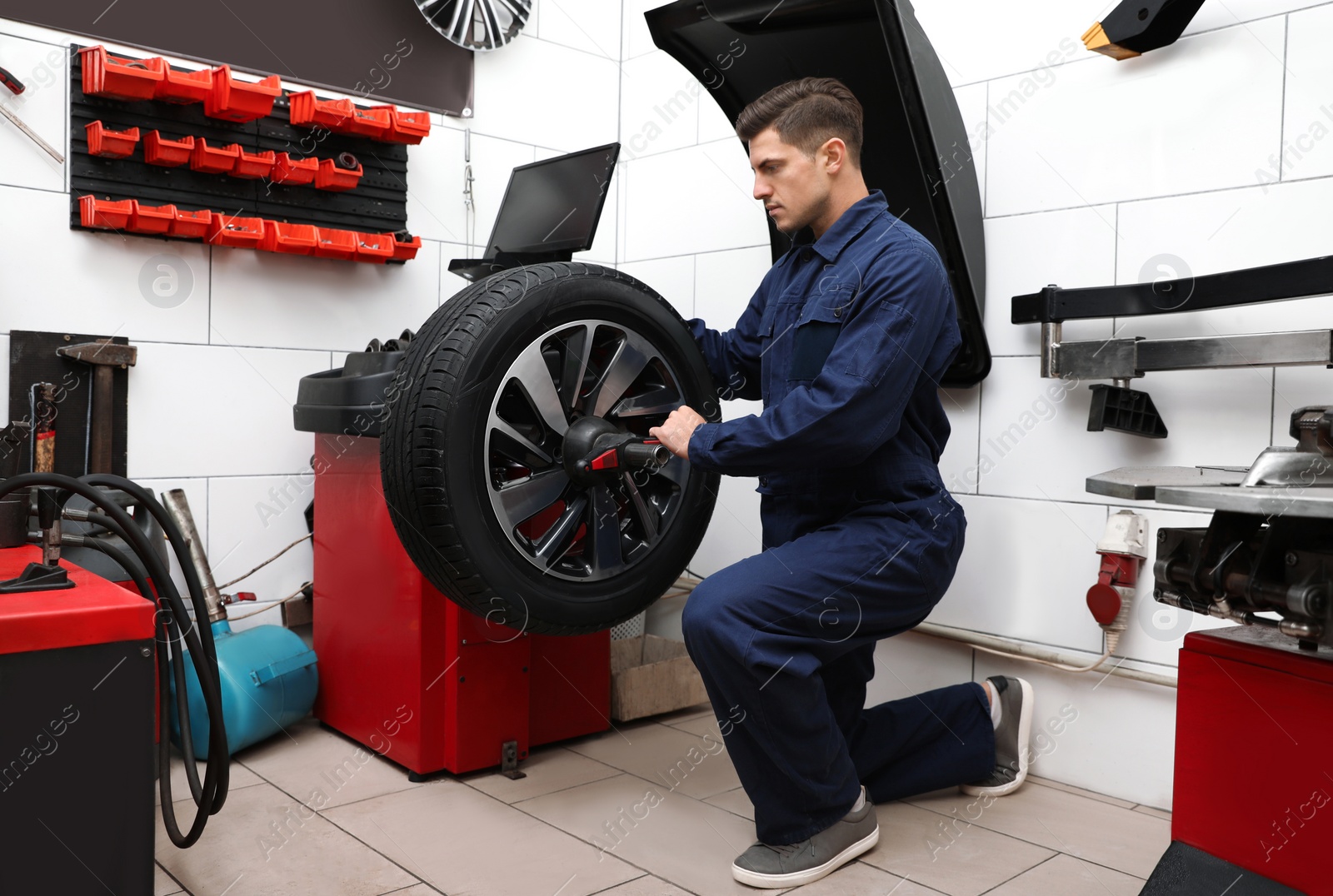 Photo of Man working with wheel balancing machine at tire service