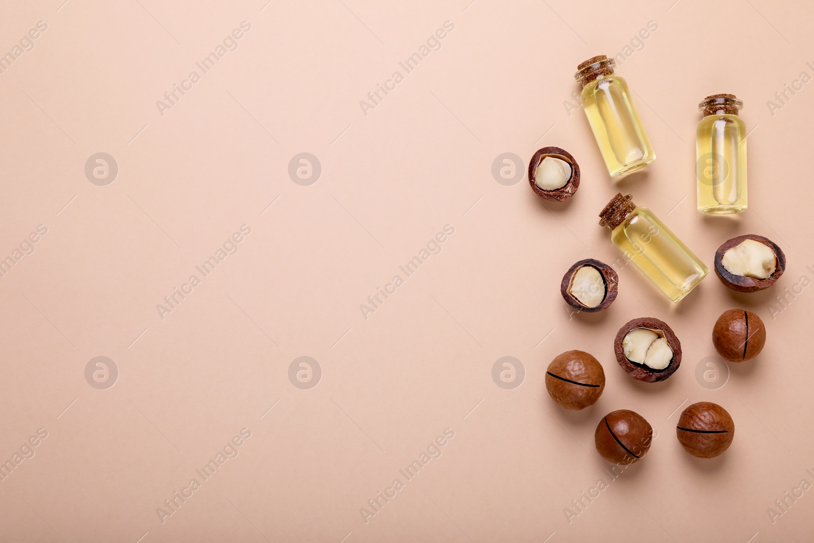 Photo of Delicious organic Macadamia nuts and cosmetic oil on beige background, flat lay. Space for text