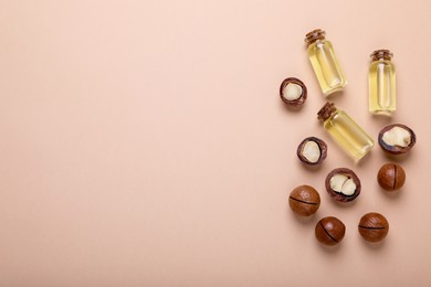 Photo of Delicious organic Macadamia nuts and cosmetic oil on beige background, flat lay. Space for text