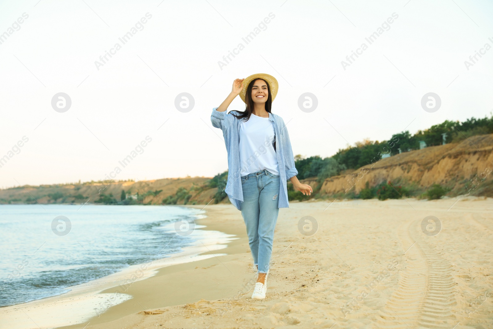 Photo of Beautiful young woman in casual outfit on beach