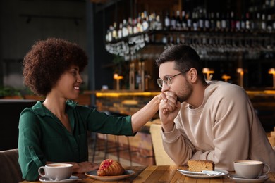 Photo of International relationships. Handsome man kissing her girlfriend's hand in cafe