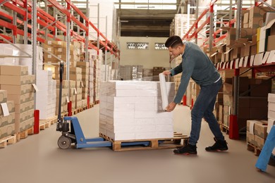 Photo of Worker wrapping boxes in stretch film at warehouse