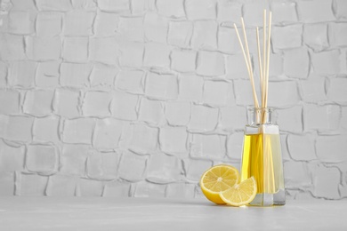 Photo of Aromatic reed freshener and lemon on table against textured wall. Space for text