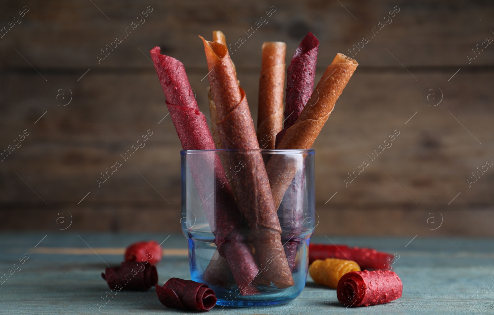 Photo of Delicious fruit leather rolls on blue wooden table
