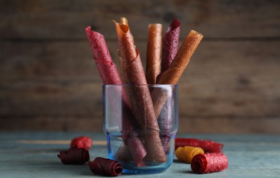 Delicious fruit leather rolls on blue wooden table