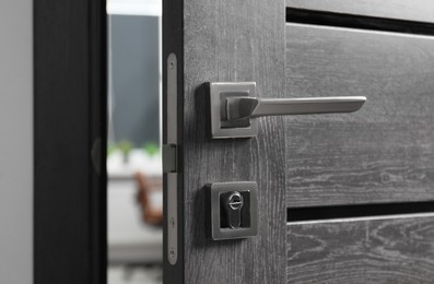 Photo of Open wooden door with metal handle, closeup