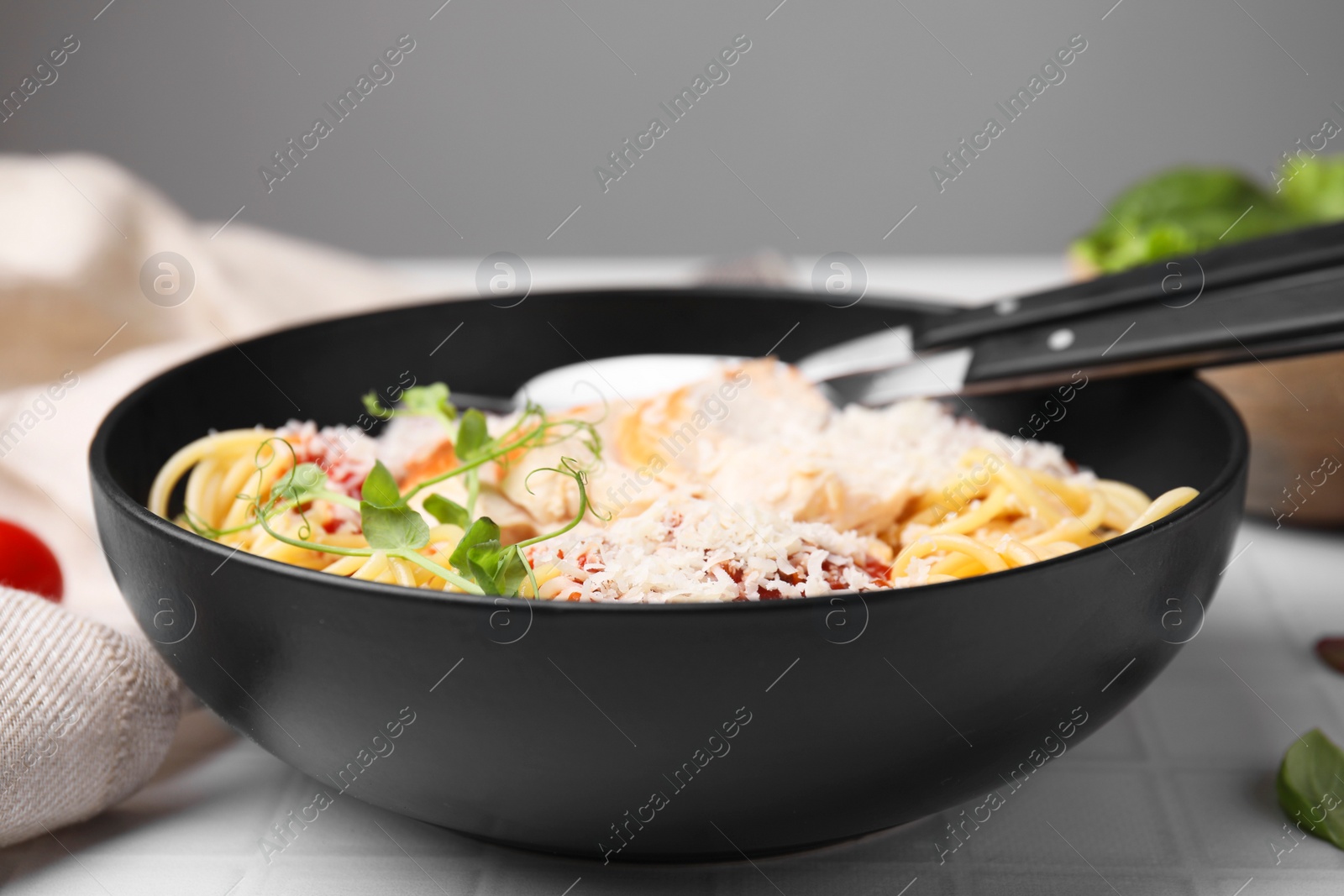 Photo of Delicious pasta with tomato sauce, chicken and parmesan cheese on white tiled table, closeup