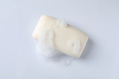 Soap with fluffy foam on white background, top view