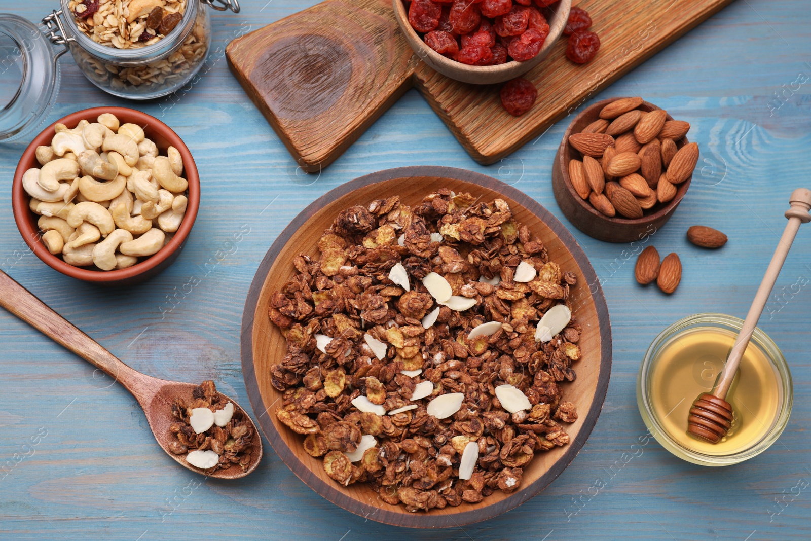 Photo of Tasty granola served with nuts and dry fruits on light blue wooden table, flat lay