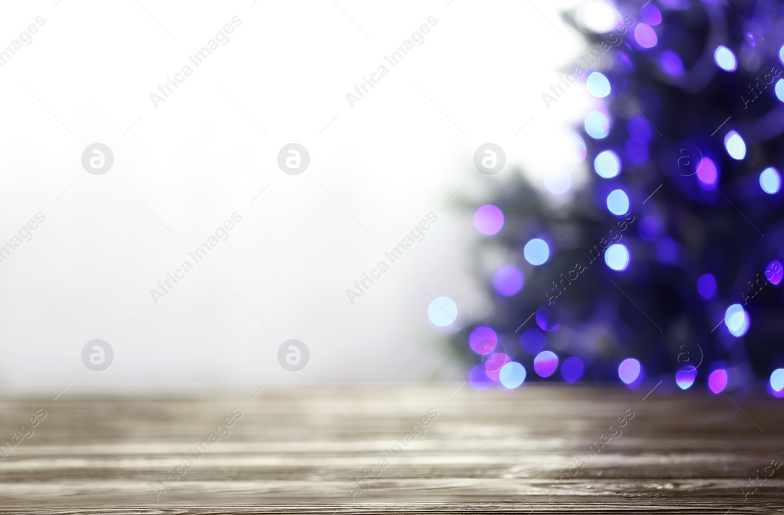 Photo of Empty table and blurred fir tree with violet Christmas lights on background, bokeh effect. Space for design