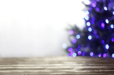 Photo of Empty table and blurred fir tree with violet Christmas lights on background, bokeh effect. Space for design