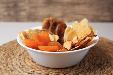Photo of Bowl with different dried fruits on wicker mat