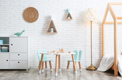 Photo of Cute children's room interior with bed and little table