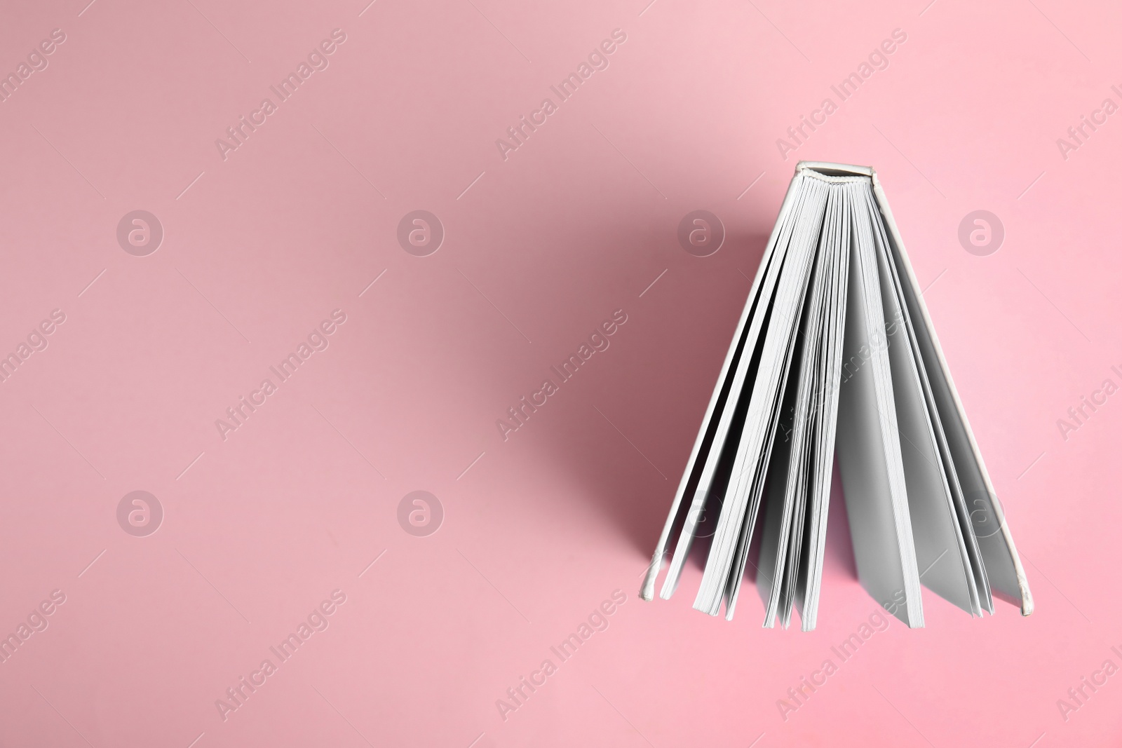 Photo of Hardcover book on pink background, top view. Space for text