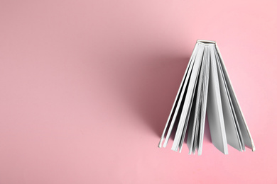 Hardcover book on pink background, top view. Space for text