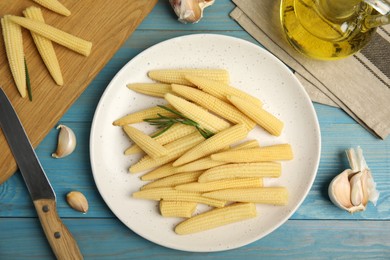 Photo of Fresh baby corn cobs on blue wooden table, flat lay