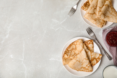 Flat lay composition with fresh thin pancakes on light grey marble table. Space for text