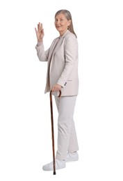 Senior woman with walking cane waving on white background