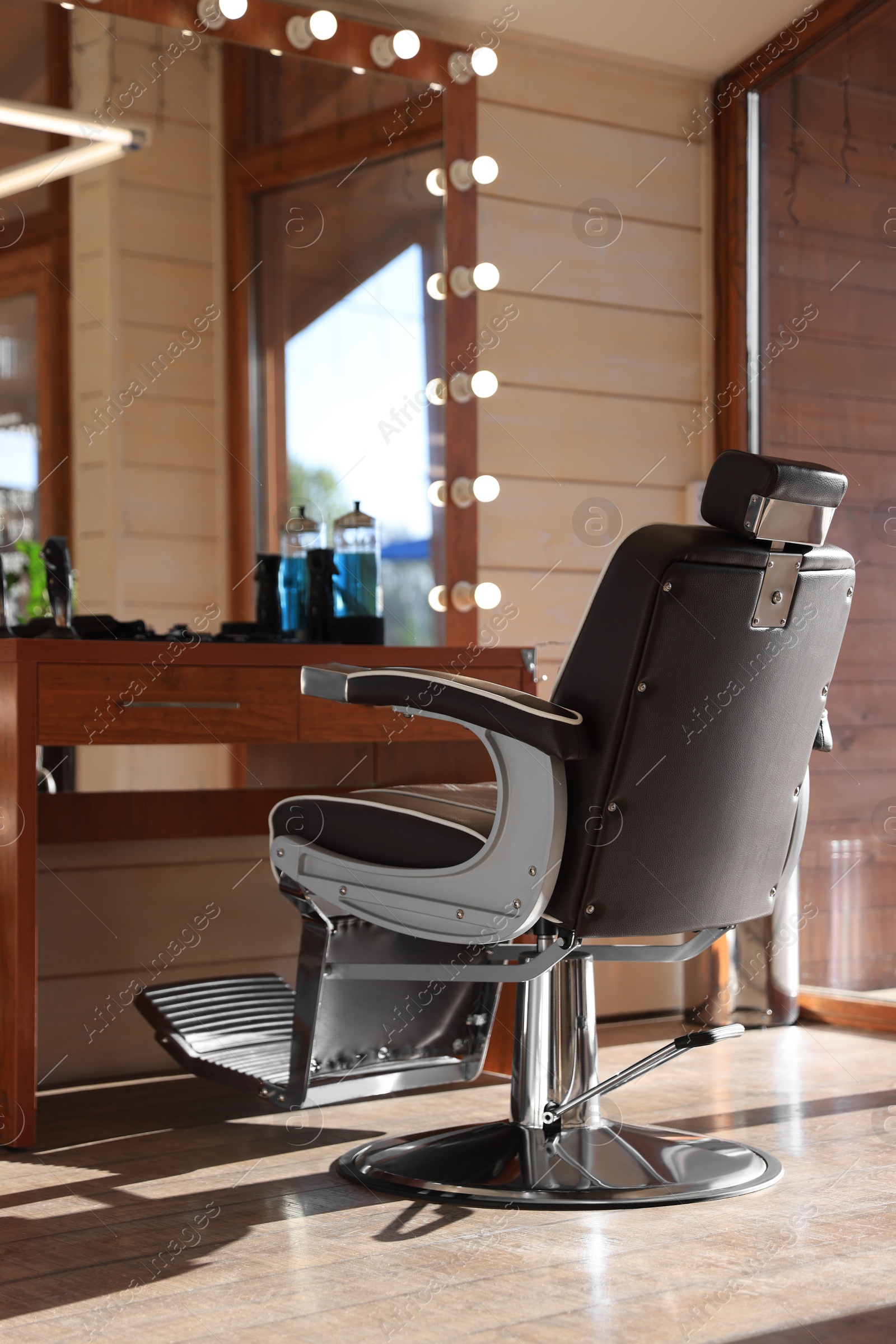 Photo of Stylish hairdresser's workplace with professional armchair and beautiful big mirror in barbershop