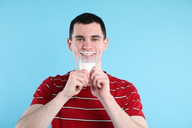 Milk mustache left after dairy product. Man drinking milk on light blue background