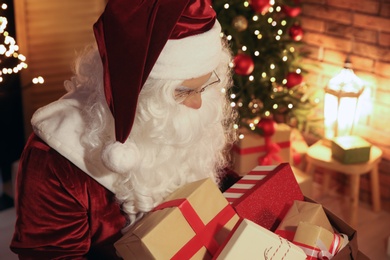 Santa Claus with bunch of gifts in festively decorated room