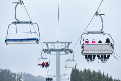 Photo of Chairlift with people at ski resort. Winter vacation