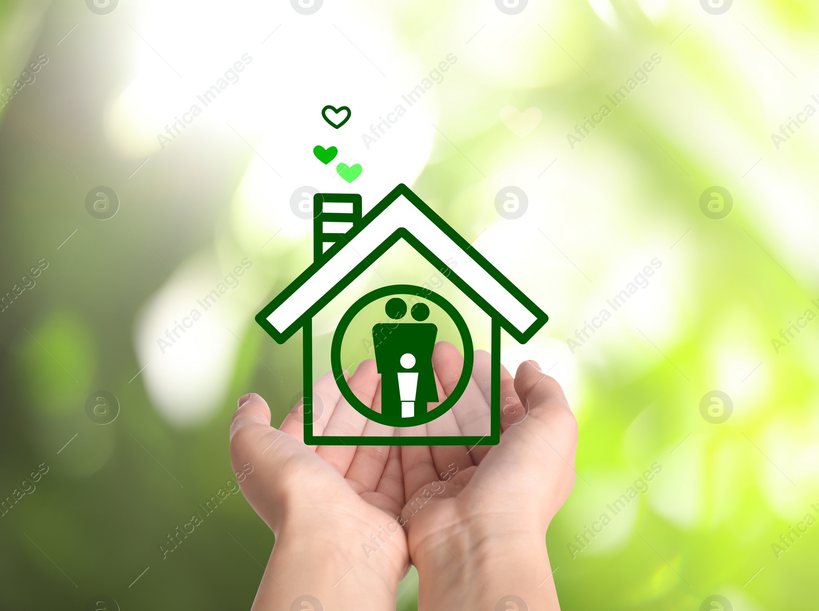 Image of Woman demonstrating illustration of house with family on blurred green background, closeup