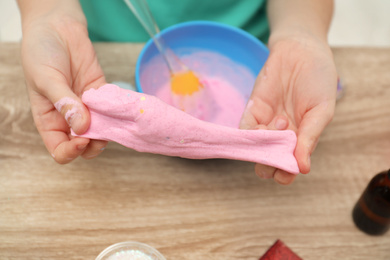 Photo of Little girl making DIY slime toy at table, closeup