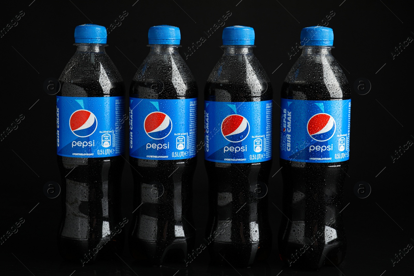 Photo of MYKOLAIV, UKRAINE - FEBRUARY 08, 2021: Plastic bottles of Pepsi with water drops on black background